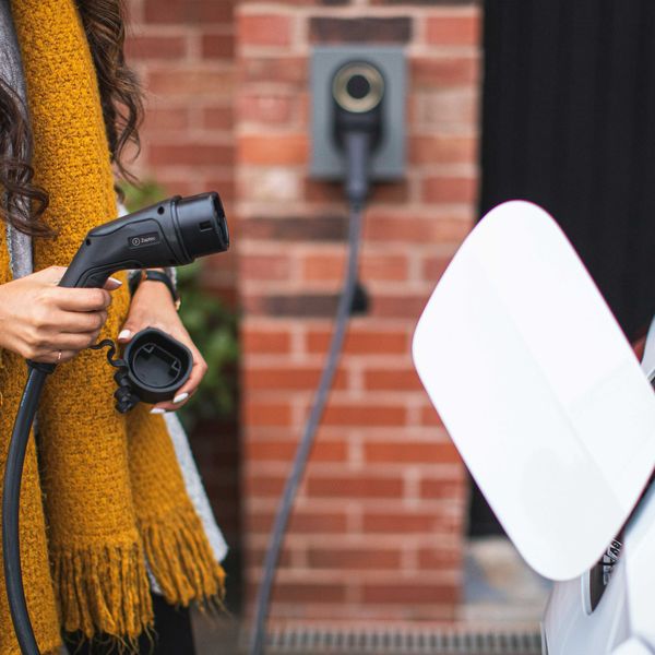 a woman with a yellow scarf attaching an electric vehicle charger to her car