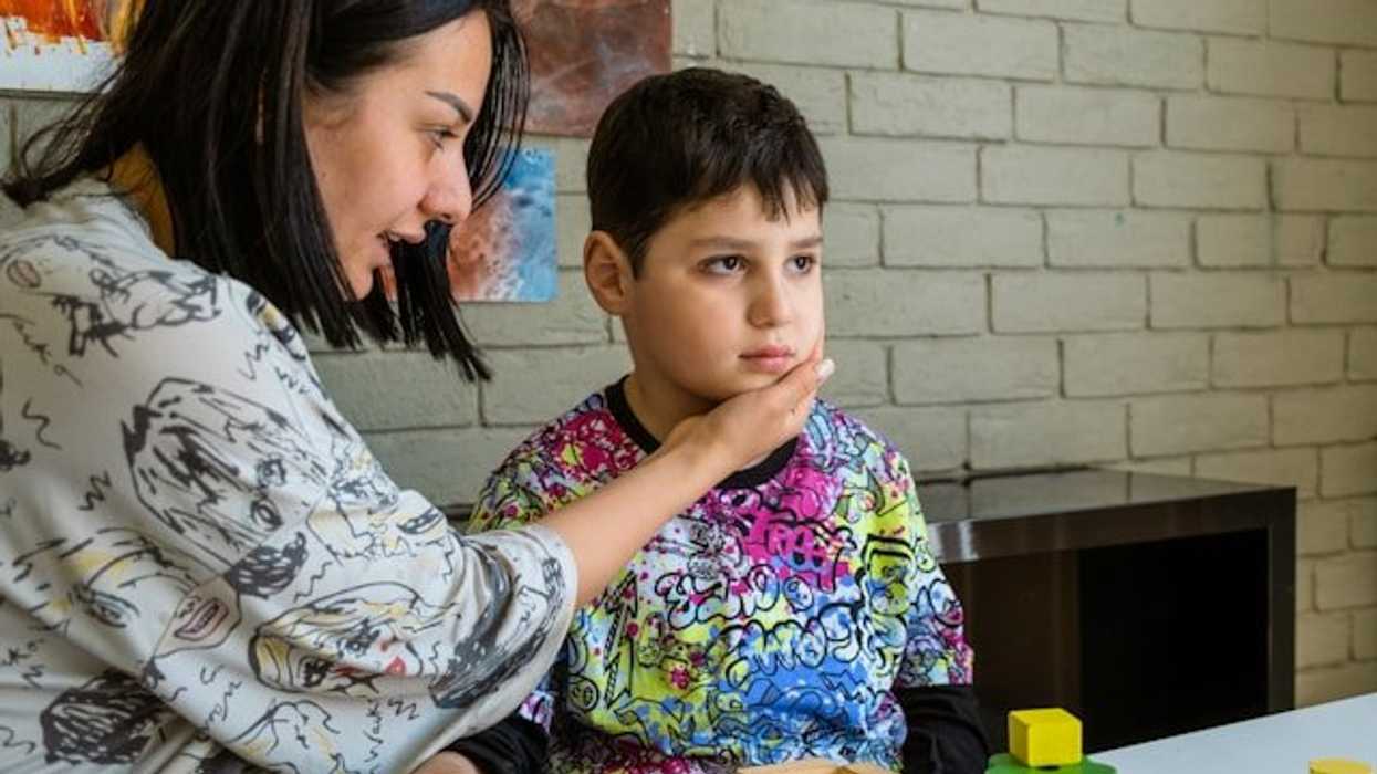 A woman with her hand on the face of a child who is looking straight ahead.