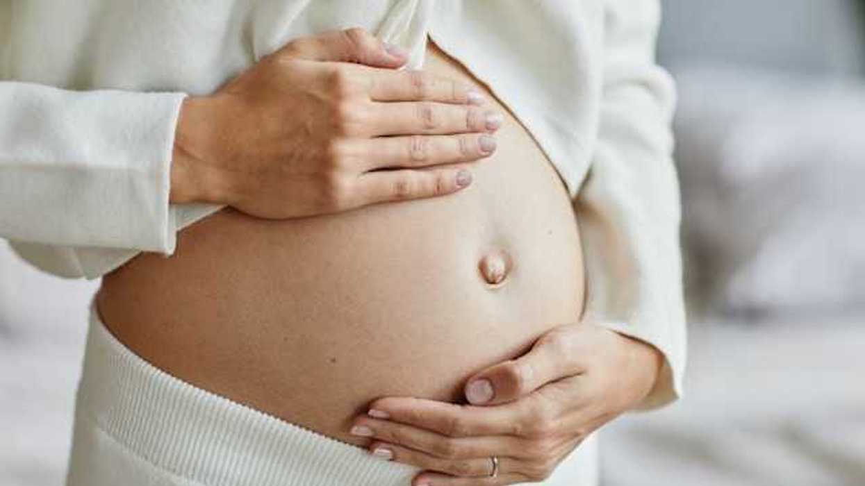 A woman with her hands cupping her pregnant belly