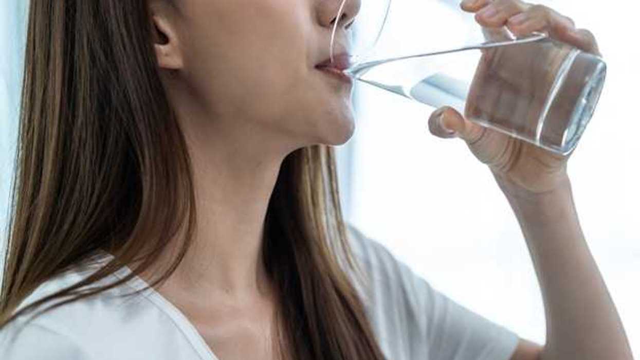 A women with brown hair drinking a glass of water