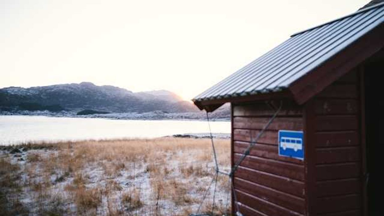 A wooden building in front of an icy landscape with water in the background