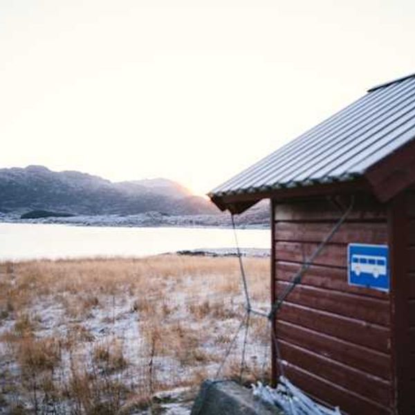 A wooden building in front of an icy landscape with water in the background