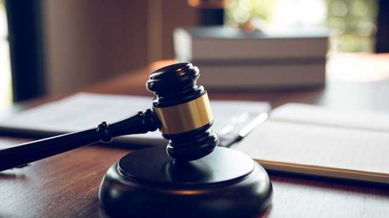 A wooden gavel on a wooden platform sitting on a desk