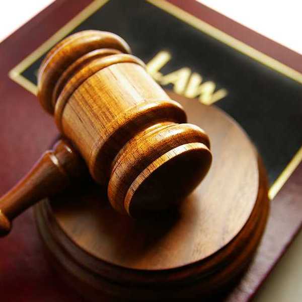 A wooden gavel sitting on top of a law book