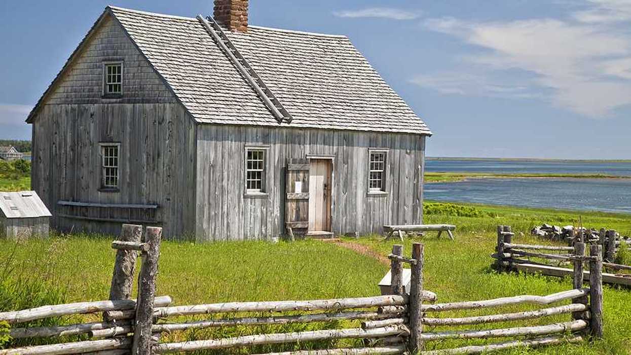 A wooden house with water in the background