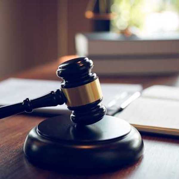 A wooden judge's gavel on a wooden desk