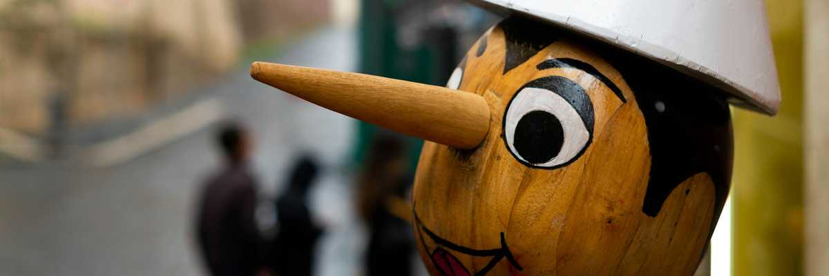 a wooden statue of pinocchio with a long nose and a white hat on its head
