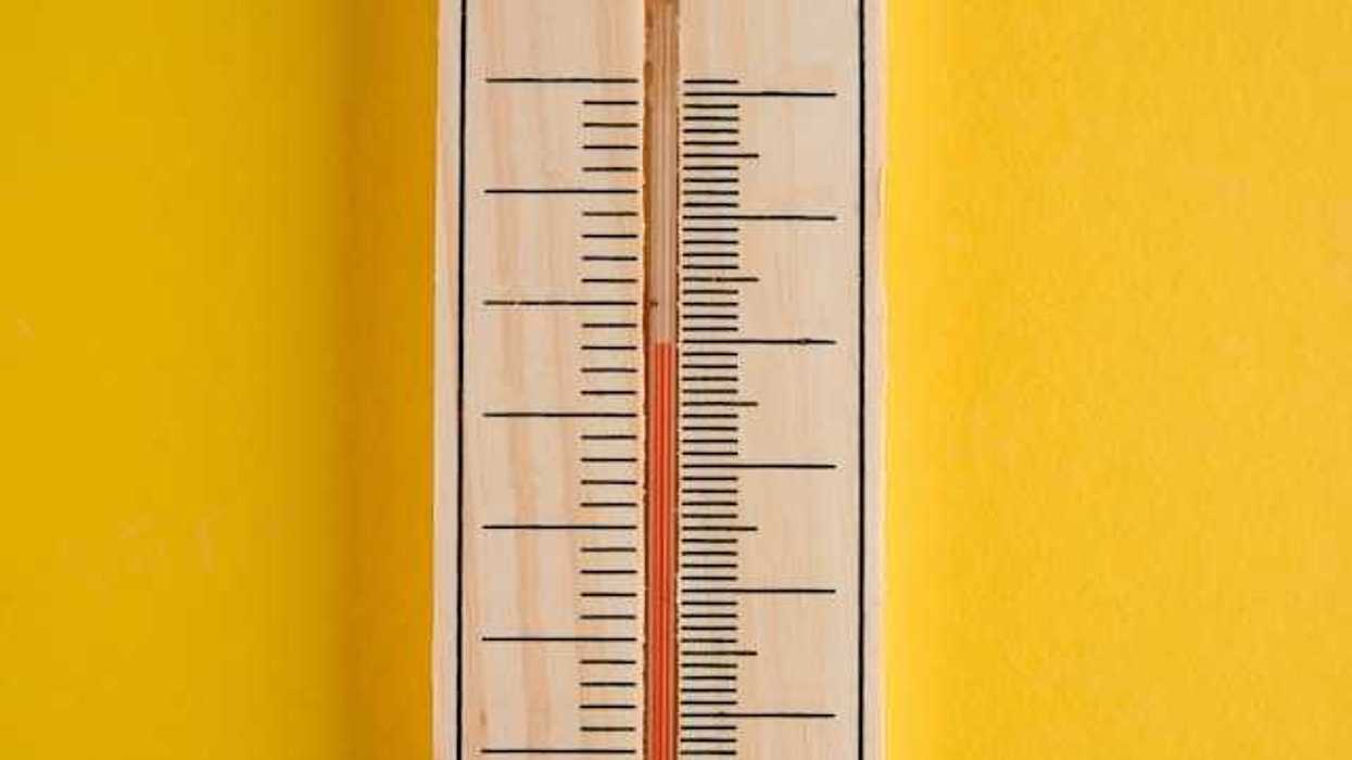 A wooden thermometer with markings on either side, at a hot temperature