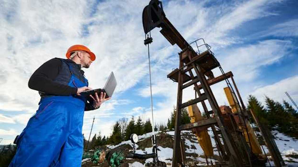 A worker inspecting an oil well in a snowy location