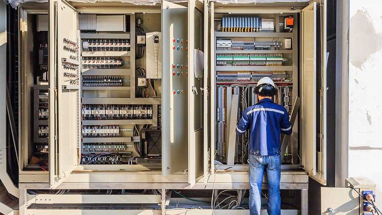 A worker installing electronics in a large industrial cabinet
