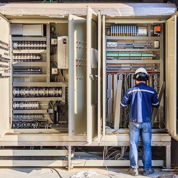A worker installing electronics in a large industrial cabinet