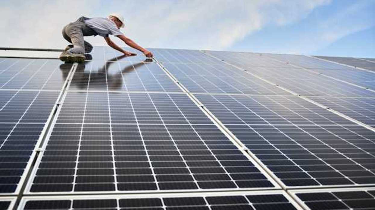 A worker installing solar panels on a roof
