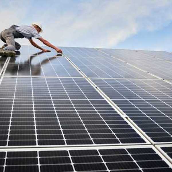 A worker installing solar panels on a roof