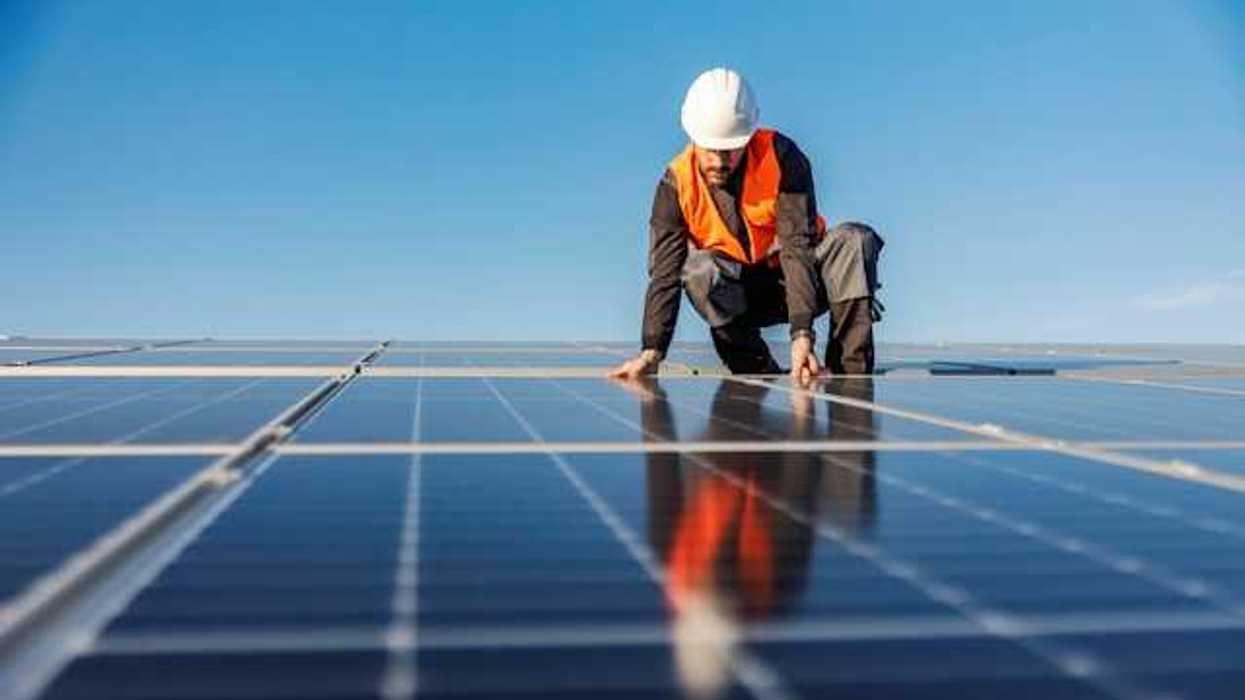 A worker installing solar panels on a roof