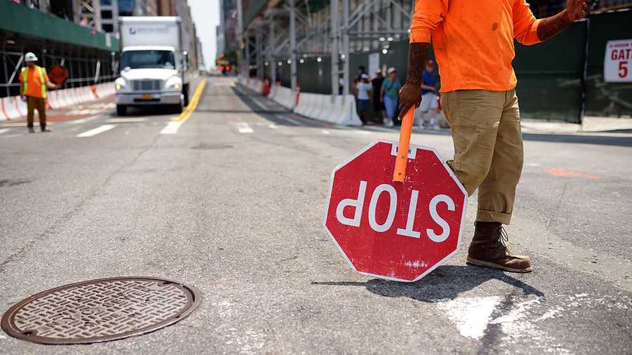 A worker with a stop sign directing traffic in a construction zone