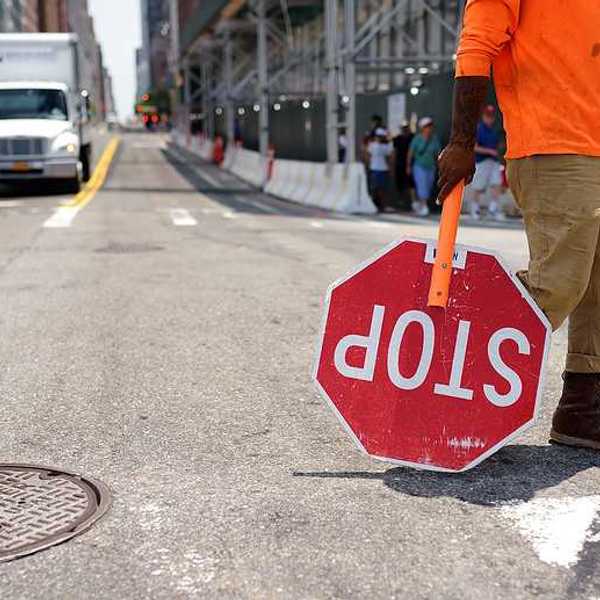 A worker with a stop sign directing traffic in a construction zone