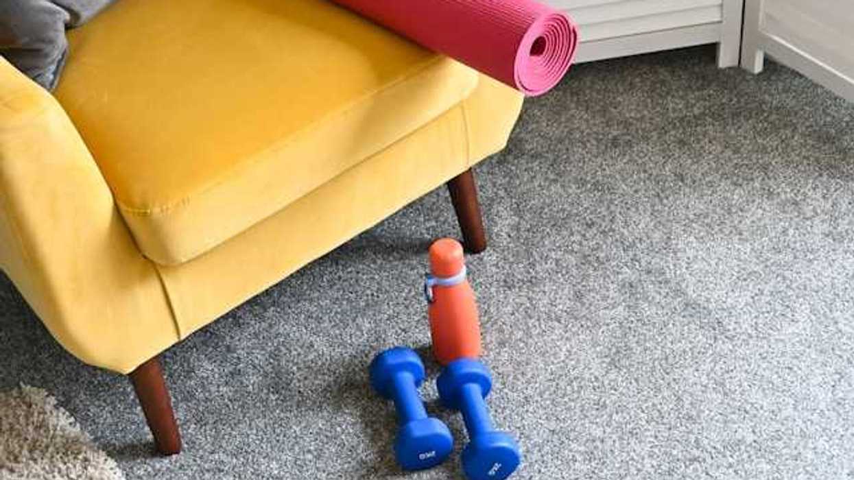 A yellow chair sitting on a grey carpeted floor with workout equipment nearby