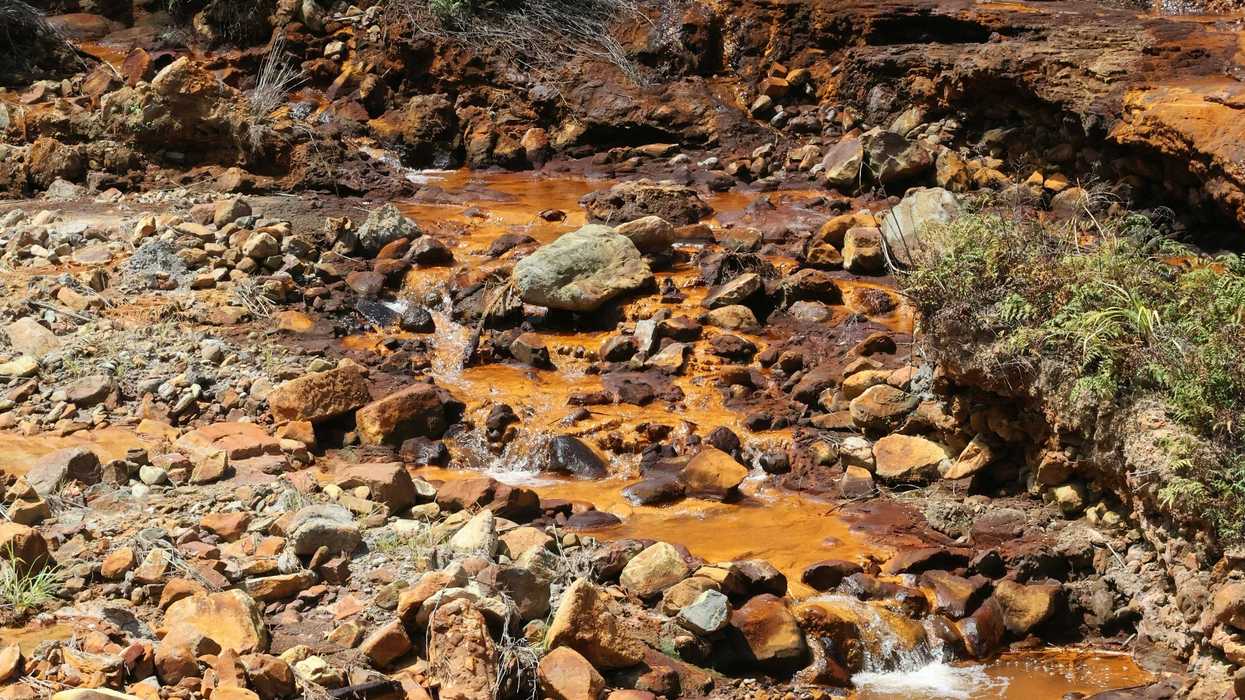 a yellow stream of contaminated water running through a rocky area.