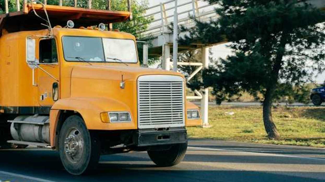 A yellow truck driving on a country road