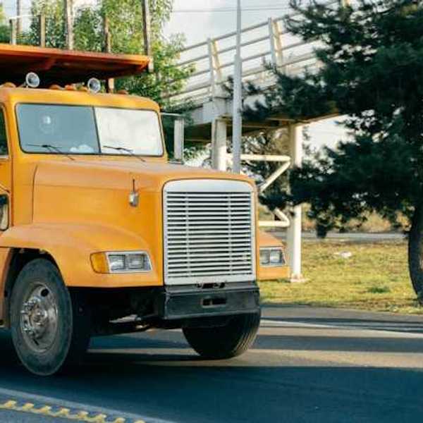 A yellow truck driving on a country road