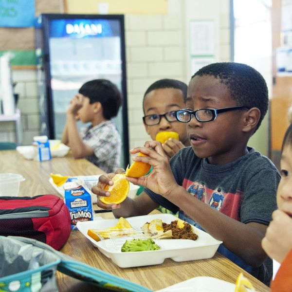 A young boy eats school lunch out of a disposable tray.