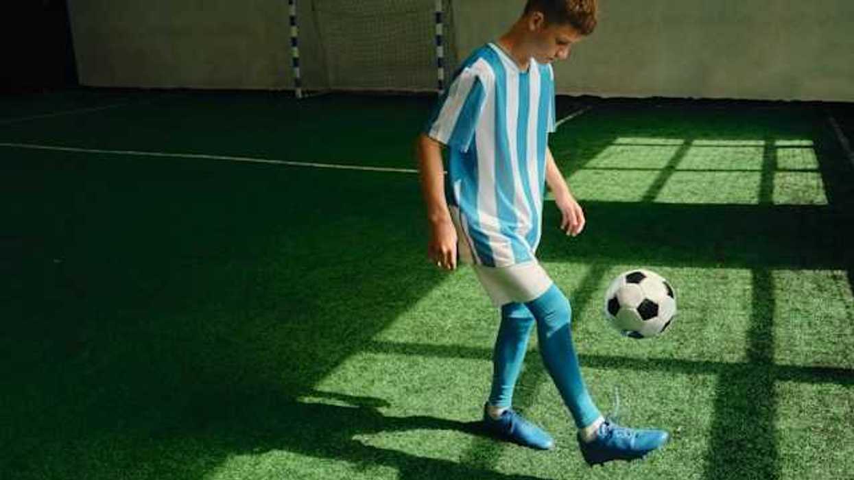 A young boy kicking a soccer ball on an artificial turf surface