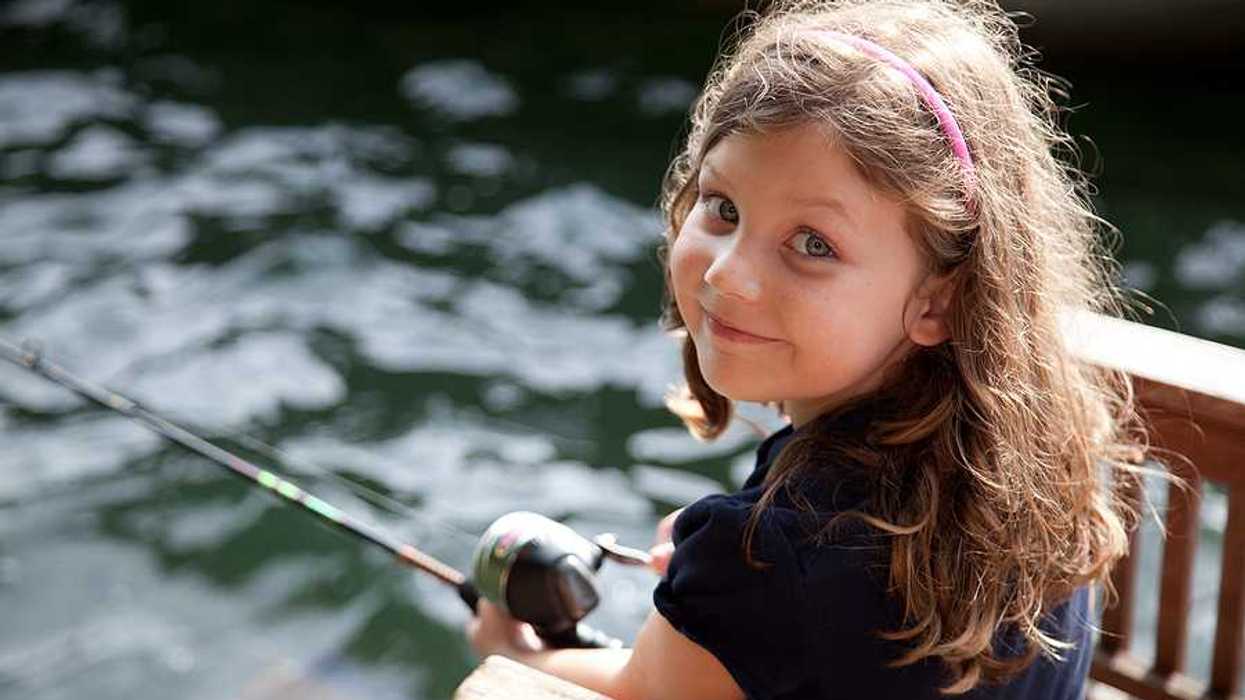 A young girl looking at the camera while fishing off a dock