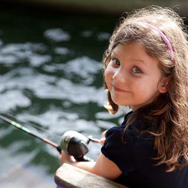 A young girl looking at the camera while fishing off a dock