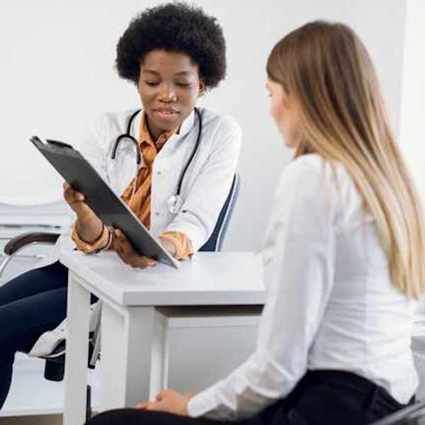 A young woman sitting at a desk with a female doctor