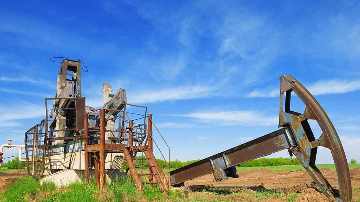 Abandoned oil pump jack in field summer day
