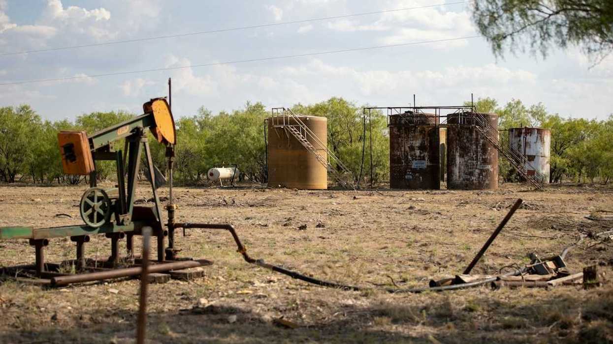 Abandoned oil well adjacent to rusting storage tanks