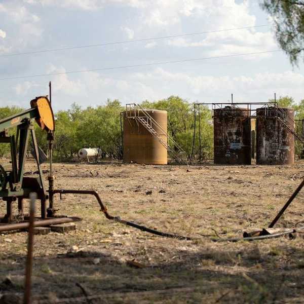 Abandoned oil well adjacent to rusting storage tanks