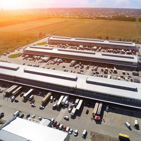 Aerial drone view of group of large modern industrial warehouse or factory buildings in suburban area