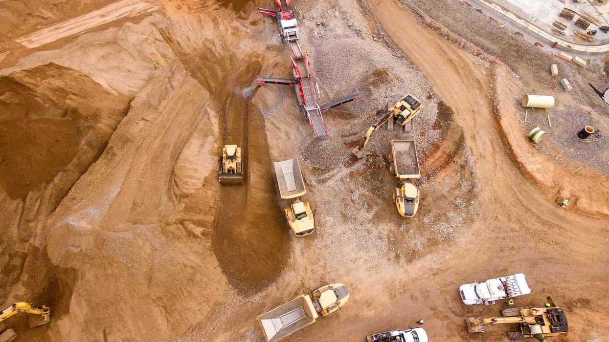 Aerial shot of mining site with dump trucks and bulldozers.