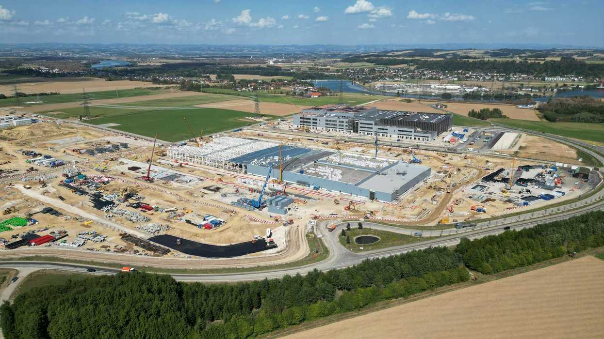 Aerial view of a large industrial construction site with cranes and unfinished buildings.
