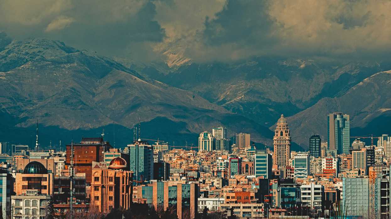 aerial view of city buildings during daytime with mountainsa nd clouds in background.