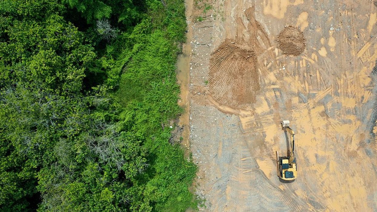 Aerial view of heavy machinery clearing a forest.