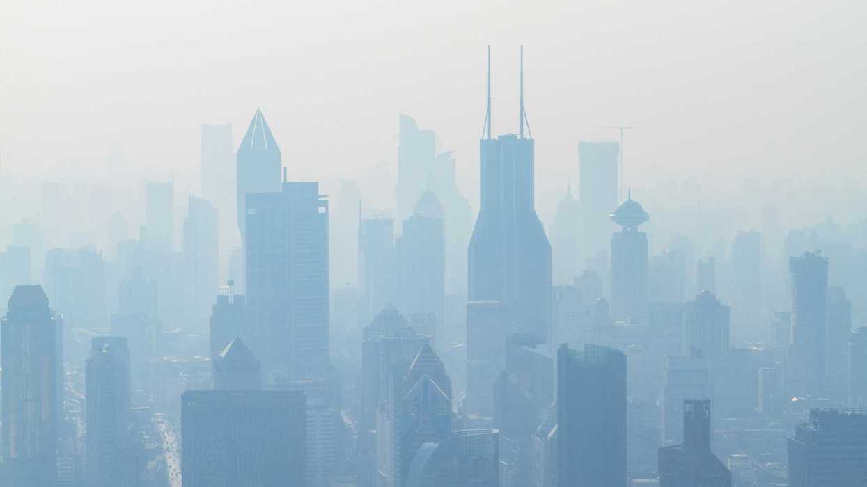 aerial view of high-rise buildings shrouded in smog or smoke.