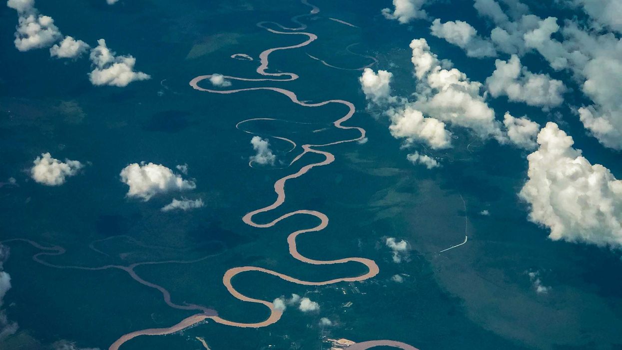 aerial view of river with white clouds above green landscape.