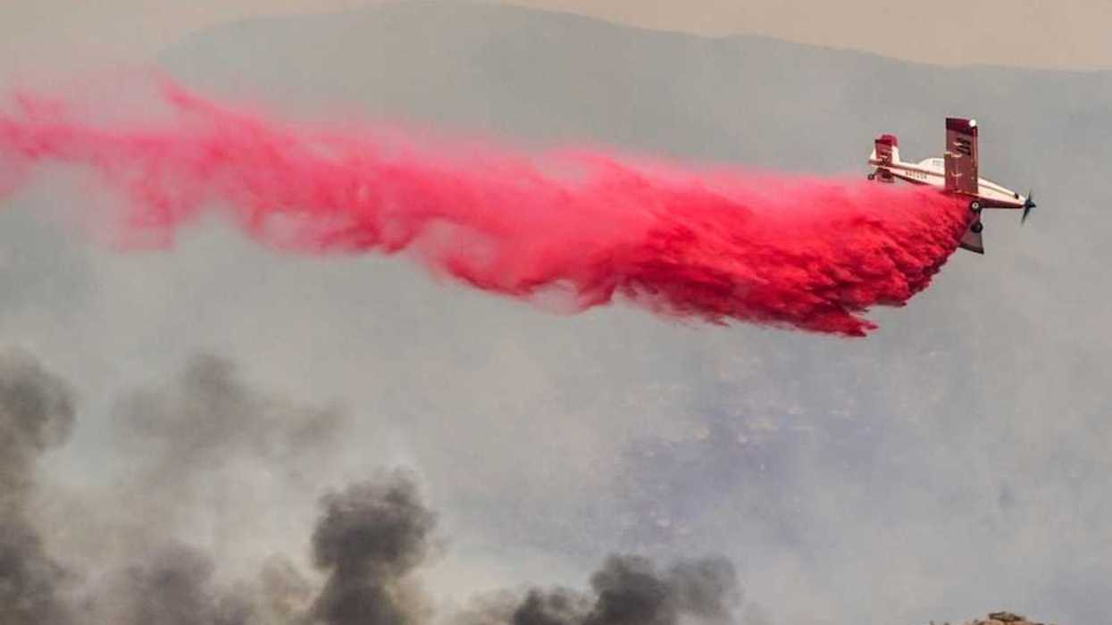 Airplane drops red fire retardant on a wildfire