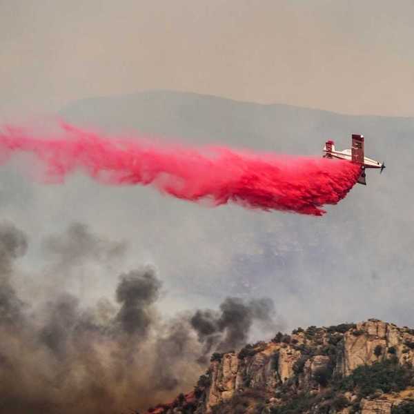 Airplane drops red fire retardant on a wildfire
