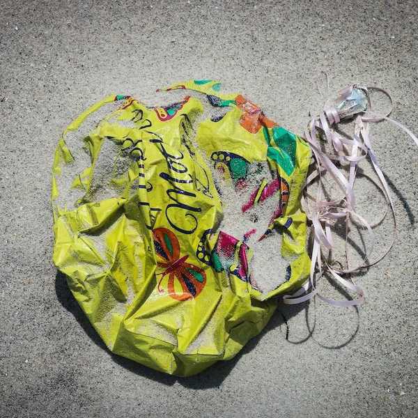 An abandoned, deflated, balloon mired in the sand