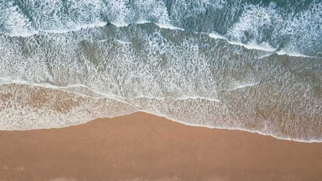An aerial view of a beach with green water and waves
