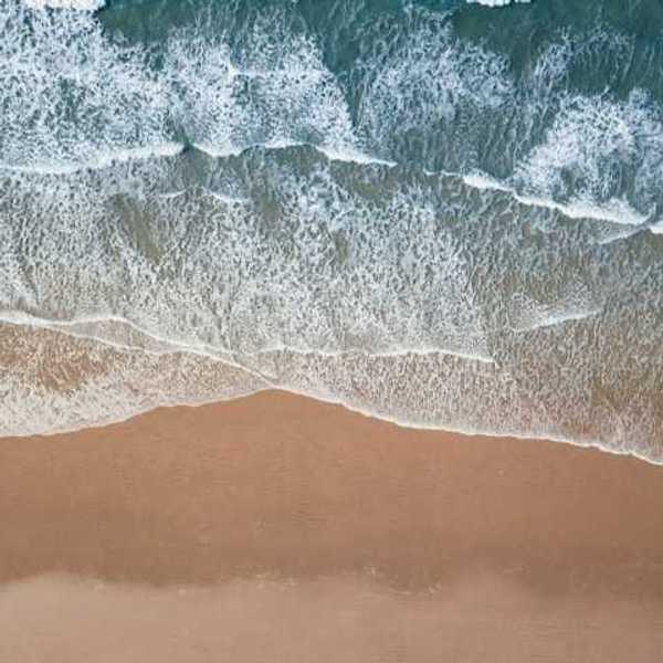 An aerial view of a beach with green water and waves