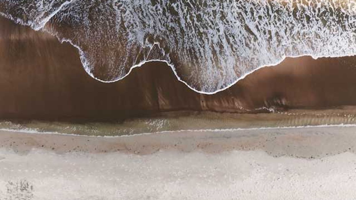 An aerial view of a beach with the waves encroaching