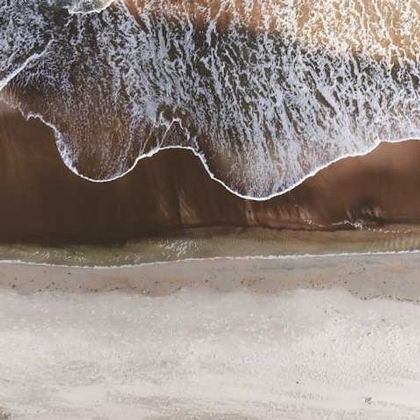An aerial view of a beach with the waves encroaching