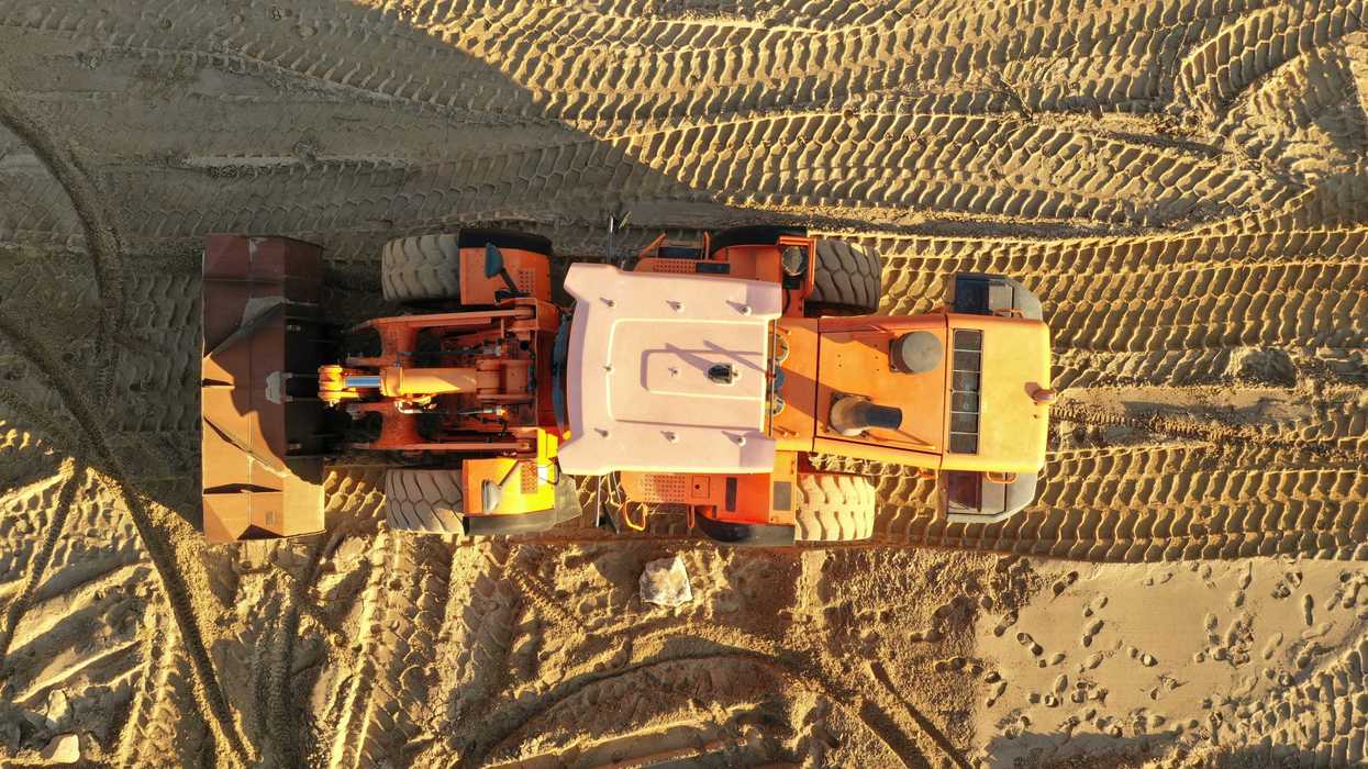 an aerial view of a bulldozer in the middle of desert sand.