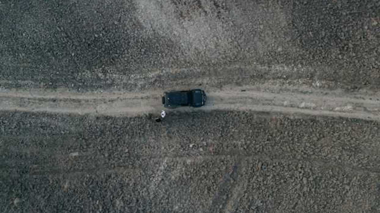 An aerial view of a car on a lonely dirt road
