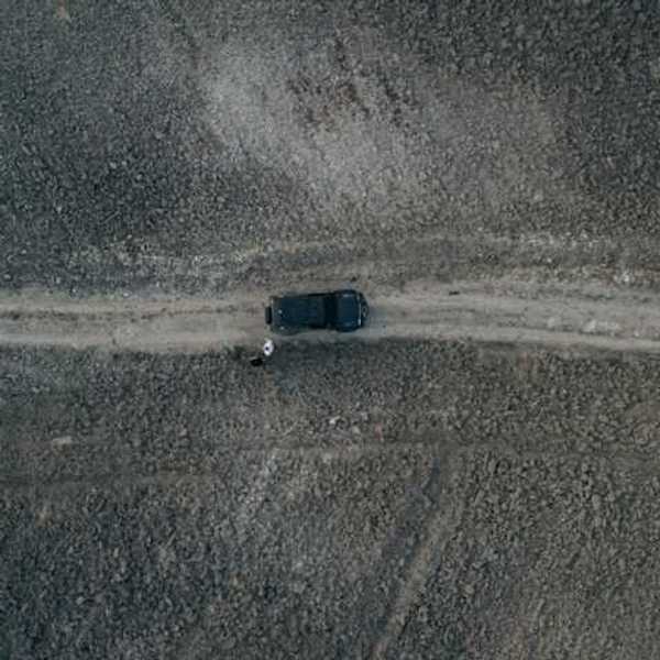 An aerial view of a car on a lonely dirt road