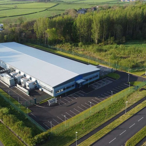 an aerial view of a data center flanked by trees, roads and green fields.